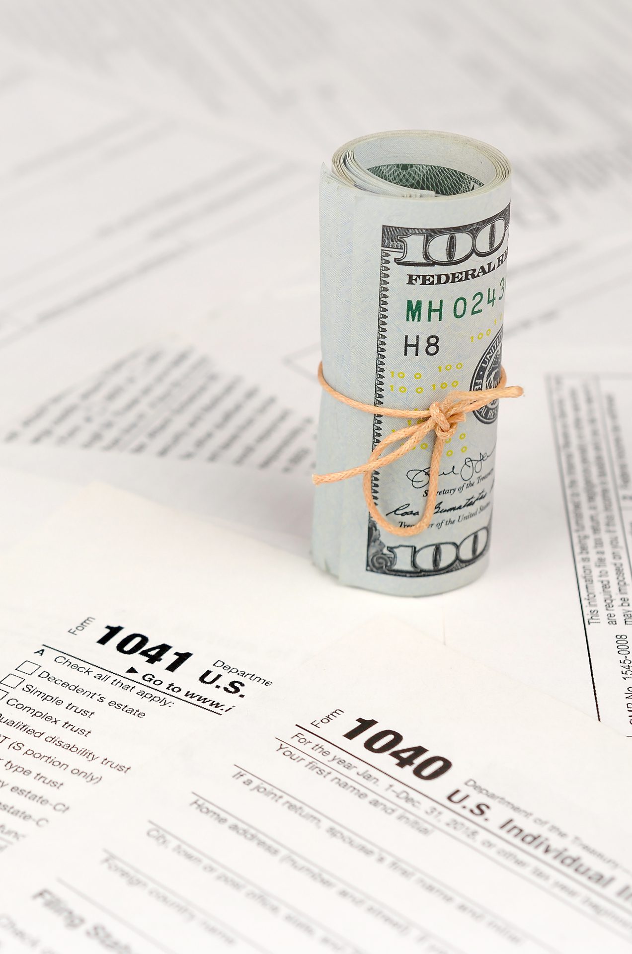 Tax forms lies near roll of hundred dollar bills. Income tax return Tax Preparation Services